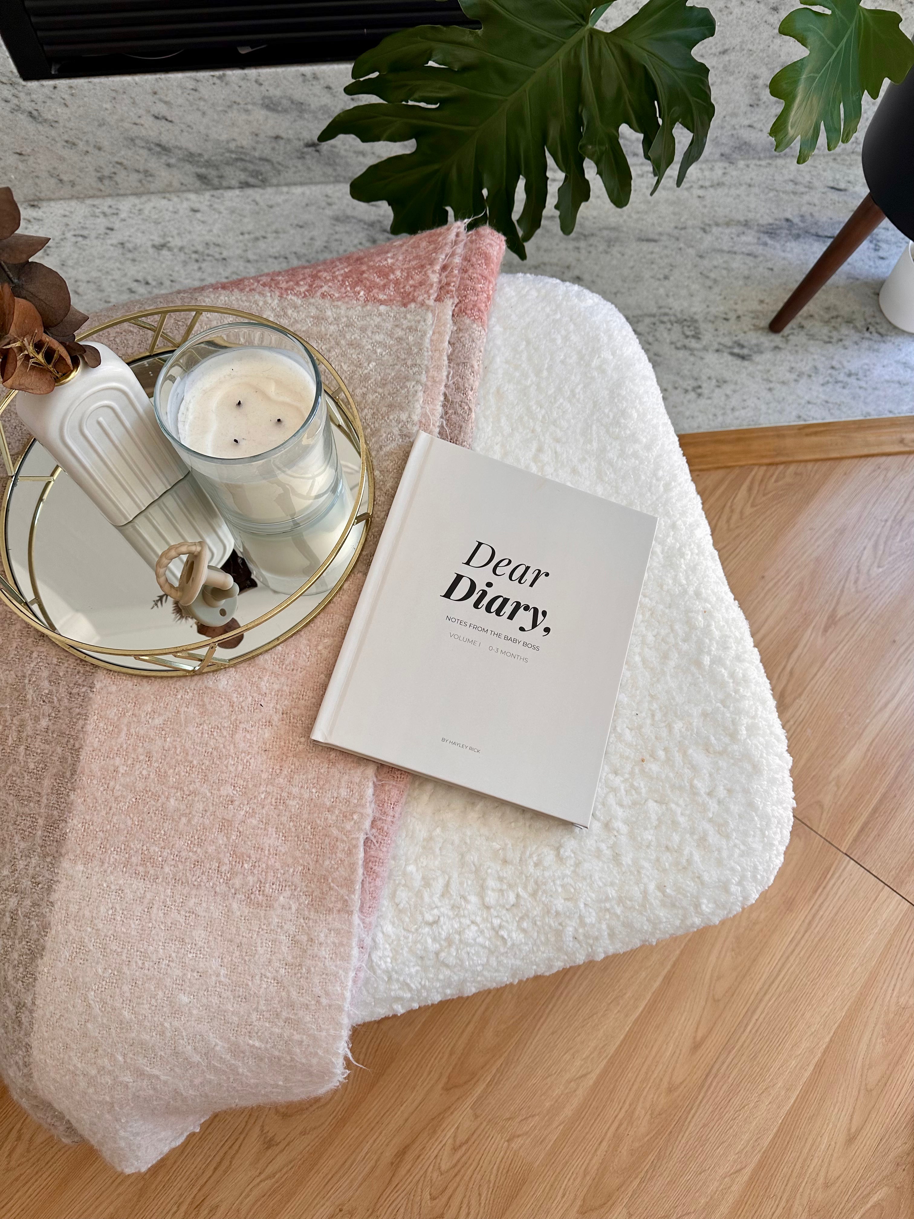 Dear Diary baby memory book displayed on a coffee table with a drink and flowers