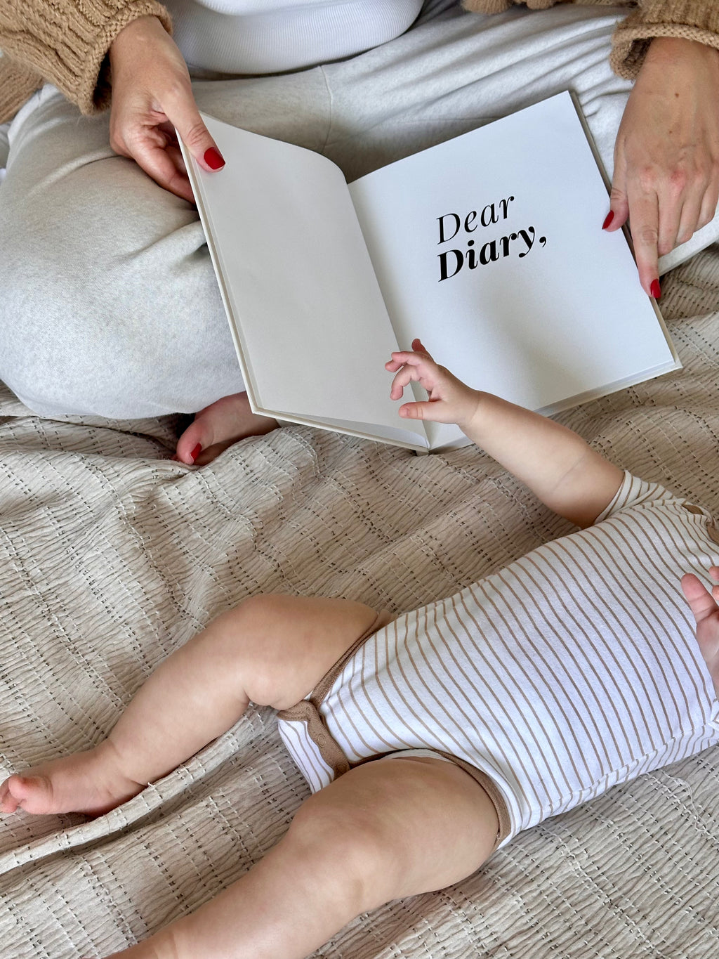 Parent holding Dear Diary baby memory book while sitting with baby
